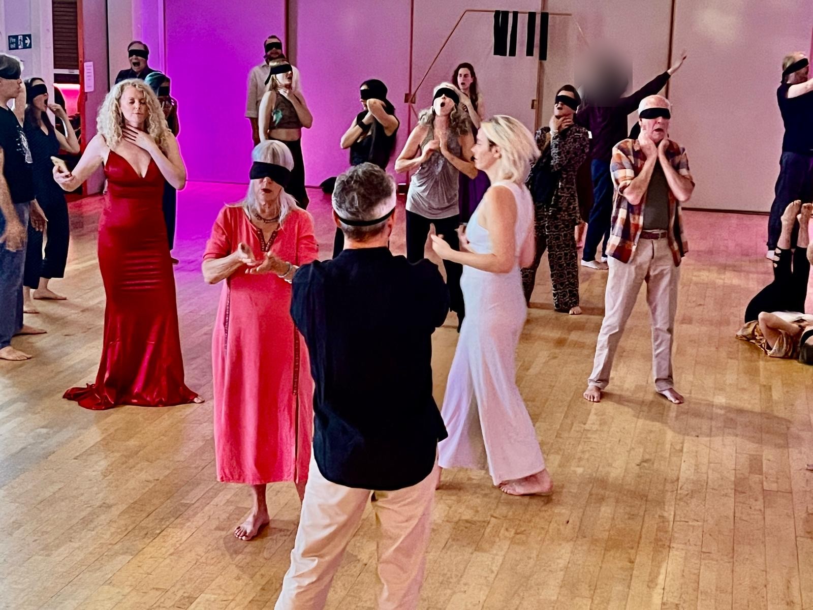 A group of participants exploring sound and movement with blindfolds, guided by the facilitators