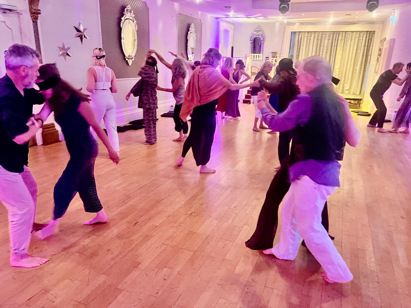Pairs moving and connecting across the room, some leading and some following with blindfolds